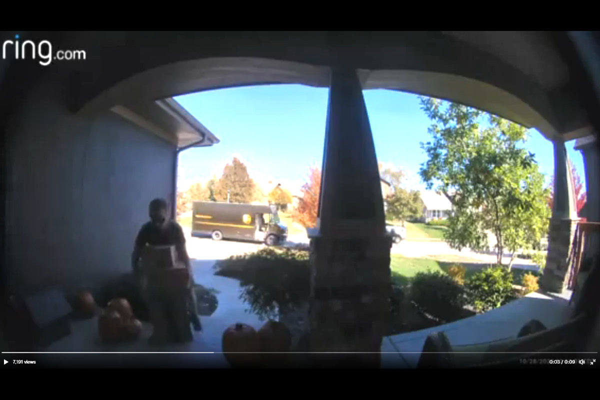 UPS driver picking up a previously delivered Amazon package and hiding it with other packages he is delivering.